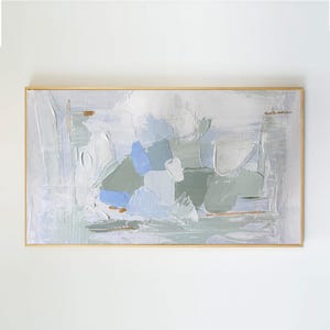 May include: A rectangular abstract painting in a thin gold frame featuring thick, textured impasto brushstrokes in shades of sage green, soft periwinkle blue, white, and light gray, with subtle horizontal accents of metallic gold paint throughout.