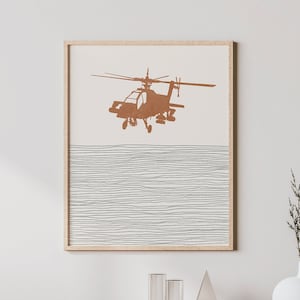 May include: A framed print of a brown helicopter silhouette against a white background with thin black lines. The print is hanging on a white wall above a light wood cabinet with a woven rattan front.