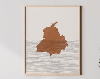 May include: A framed art print featuring a brown map outline over a beige background, with horizontal lines below. The artwork is displayed above a light wood cabinet with a white vase and decorative items.