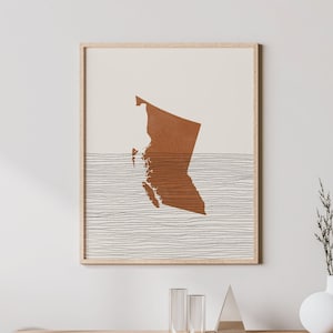 May include: A minimalist living room interior with a wooden console table, a chair, and a framed print of a brown outline of a map on a white background with thin black lines.