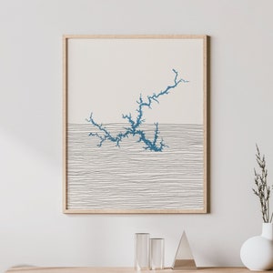 Può includere: Un interno di soggiorno minimalista con una consolle in legno, una sedia e una stampa incorniciata di un design astratto blu su sfondo bianco.