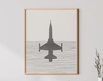 Peut inclure: Une impression encadrée d'une silhouette noire d'un avion à réaction volant au-dessus d'un fond rayé blanc et gris. L'impression est accrochée à un mur blanc au-dessus d'un meuble en bois clair avec une porte en rotin tissé.