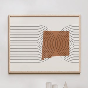 May include: A framed print with a minimalist geometric design featuring a brown shape outlined by black concentric circles against a white background.