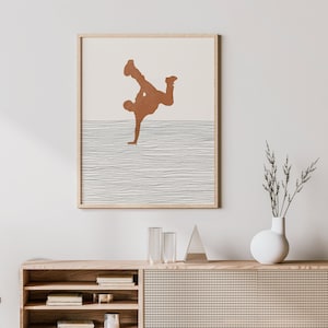 Könnte beinhalten: Ein gerahmter Druck einer braunen Silhouette einer Person, die einen Handstand auf einem Hintergrund aus dünnen, weißen Linien macht.