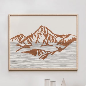以下が含まれることがあります： 茶色と白のミニマルな山脈のイラストが描かれた額装されたプリント。プリントは白い壁に、木製の棚の上に置かれた花瓶と装飾品の上に飾られています。