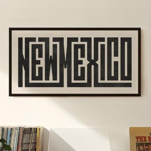 May include: A framed black and white print of the word "NEW MEXICO" in a maze-like design hangs above a record player and vinyl records. A "Best of The Beach Boys" album cover is displayed nearby.