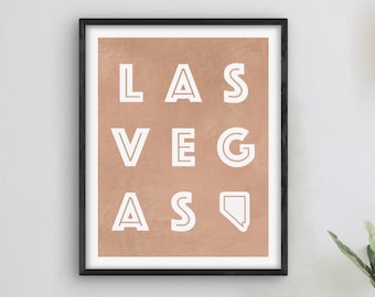 May include: A framed print with a brown background and white text that reads "LAS VEGAS" with the outline of the state of Nevada.