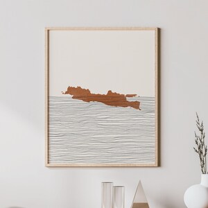 Può includere: Un interno di soggiorno minimalista con una consolle multimediale in legno, una sedia bianca e una stampa incorniciata di un'isola marrone con linee bianche su uno sfondo beige.