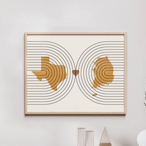 May include: A minimalist art print featuring the outlines of Texas and South Korea, connected by a heart, on a white background with black concentric circles.