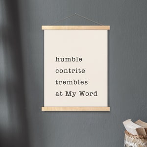 May include: A framed print with the text "humble contrite trembles at My Word" on a white background. The frame is made of natural wood and is hanging on a gray wall.