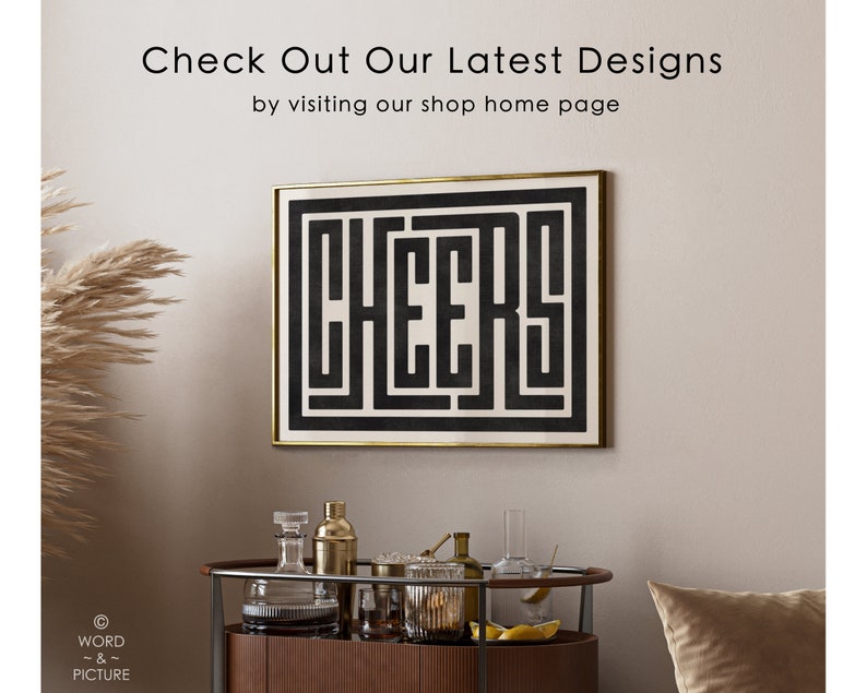 May include: Black and white geometric print with the word "CHEERS" in a maze-like design. The print is framed in a gold frame and hanging on a beige wall.
