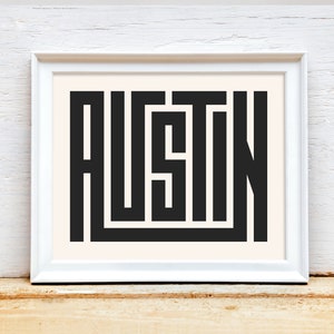 K&ouml;nnte beinhalten: Ein wei&szlig;er gerahmter Druck mit dem Wort "AUSTIN" in schwarzen, stilisierten Buchstaben.