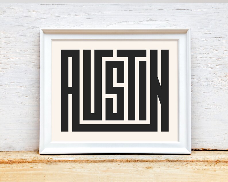 K&ouml;nnte beinhalten: Ein wei&szlig;er gerahmter Druck mit dem Wort "AUSTIN" in schwarzen, stilisierten Buchstaben.