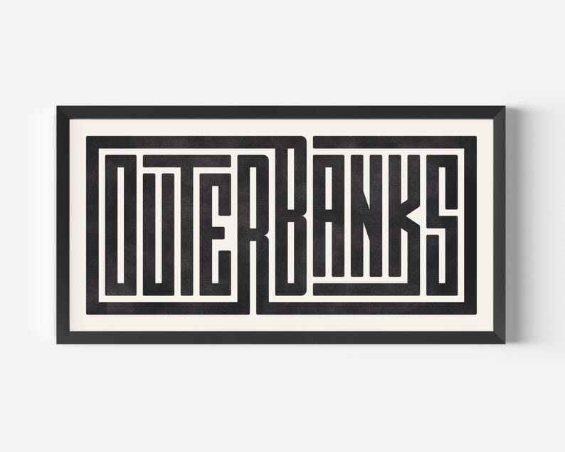May include: Black and white graphic print of the word "OUTER BANKS" in a bold, geometric font style. The print is framed in a black frame.