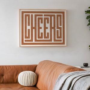 May include: A framed print with the word "CHEERS" in a brown maze-like design on a white background.