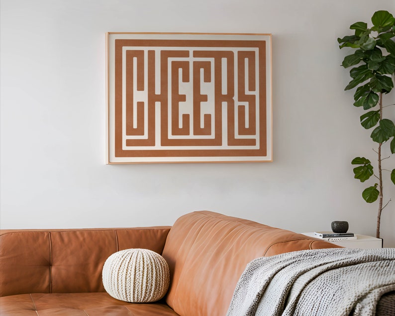 May include: A framed print with the word "CHEERS" in a brown maze-like design on a white background.
