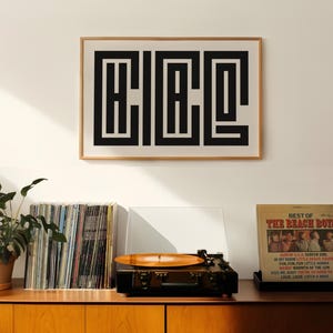 Puede incluir: Una impresi&oacute;n geom&eacute;trica en blanco y negro enmarcada de la palabra "CHIC" colgada en una pared blanca sobre un tocadiscos y una estanter&iacute;a de discos de vinilo. El tocadiscos est&aacute; reproduciendo un disco de The Beach Boys.