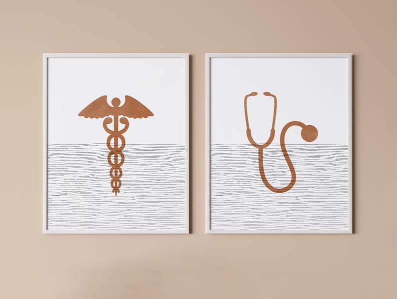 May include: Two framed prints with a white background and a brown line pattern. The print on the left features a copper-colored medical symbol, the caduceus. The print on the right features a copper-colored stethoscope.