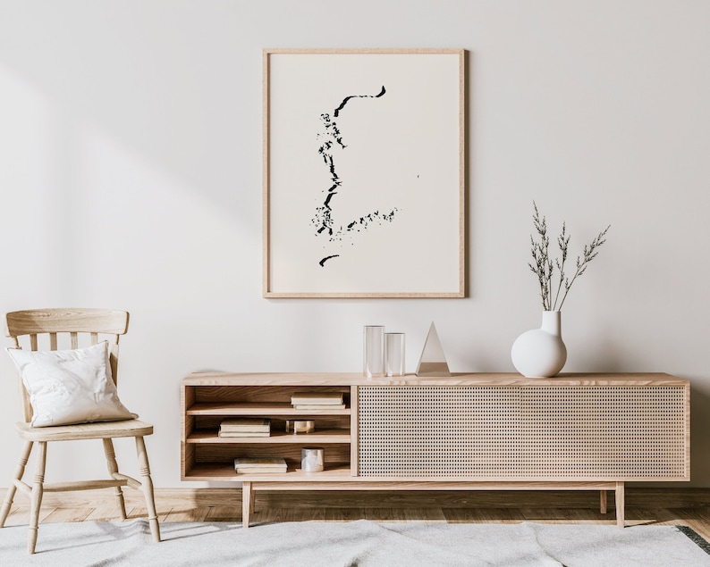 May include: A light wood media console with a woven cane front and open shelves. The console is decorated with a black and white abstract art print, a vase with dried branches, and two clear glass vases.