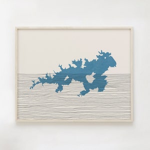May include: A framed print of a blue island silhouette with thin black lines representing waves on a cream background.