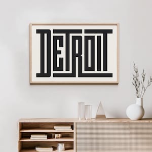 May include: A black and white framed print with the word "DETROIT" in a bold, geometric font.