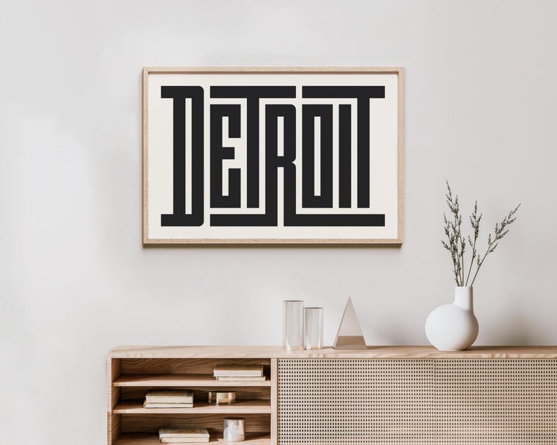 May include: A black and white framed print with the word "DETROIT" in a bold, geometric font.
