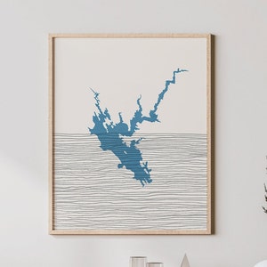 May include: A framed print of a blue silhouette of a lake or bay with a white background. The lake is surrounded by thin black lines that resemble waves.