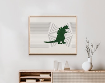 May include: A framed print of a green monster silhouette walking through a series of black and white concentric circles. The print is hanging on a white wall above a wooden shelf with books and a vase with dried flowers.