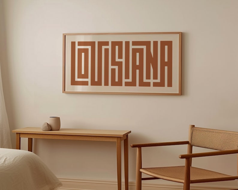 Puede incluir: Una impresi&oacute;n enmarcada con la palabra "LOUISIANA" en una fuente geom&eacute;trica marr&oacute;n sobre un fondo blanco.
