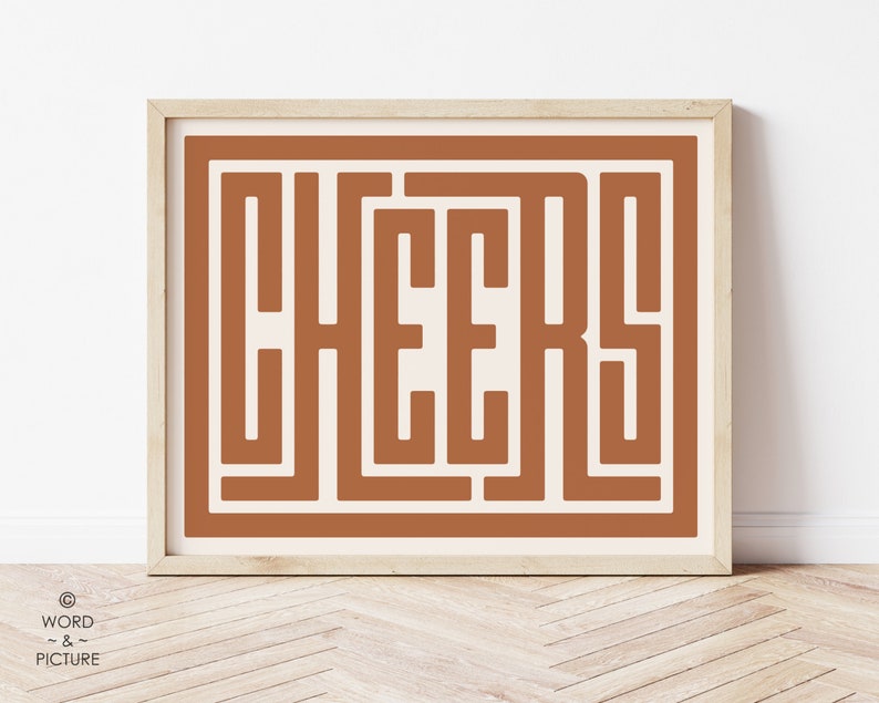 May include: A framed print with a brown background and the word "CHEERS" in a stylised font.