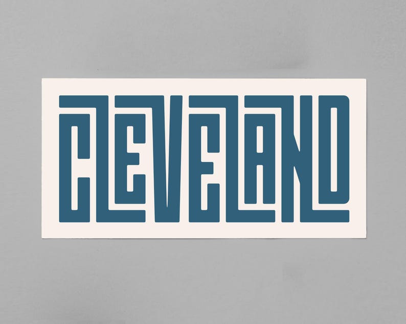 May include: A white sticker with the word "CLEVELAND" written in a blue, geometric font.