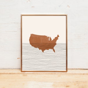 May include: A framed print of a brown outline of the United States map with a white and gray striped background.