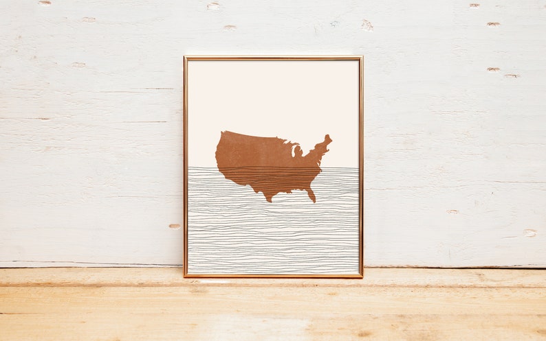 May include: A framed print of a brown outline of the United States map with a white and gray striped background.