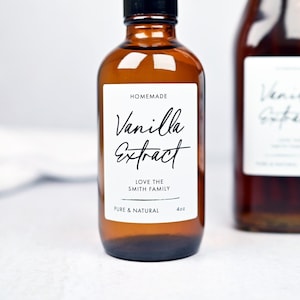 May include: Two amber glass bottles of vanilla extract. The first bottle has a black cap and a white label that reads "Homemade Vanilla Extract" with the text "Love the Smith Family" and "Pure & Natural". The second bottle has a swing top and a white label.