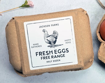 May include: A carton of fresh, free-range eggs. The brown cardboard container has a label with a hen illustration and the words "Fresh Eggs Free Range Half Dozen". A few brown eggs are visible in a separate carton.