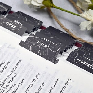 May include: Black and white patterned bookmarks with the names of books of the Bible, including Song of Songs, Isaiah, Psalms, Jeremiah, Proverbs, and Ecclesiastes.