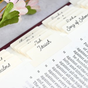 May include: Close-up of a Bible with index tabs for different books, including Psalms, Isaiah, Esther, and Song of Solomon.