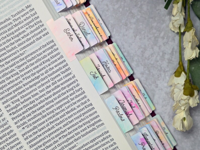 May include: A close-up of a Bible with colourful bookmarks for each book of the Bible. The bookmarks are watercolour painted with a variety of colours and designs.