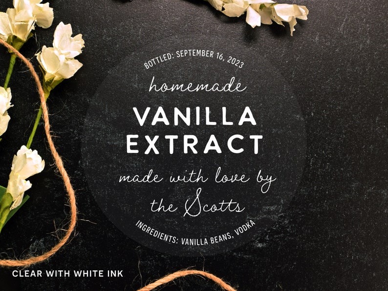 May include: A clear, round label with white text reading "homemade VANILLA EXTRACT" with the text "made with love by the Scotts." The label also includes the bottling date and ingredients. The label is surrounded by white flowers and twine.