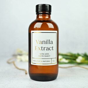 Puede incluir: Una botella de vidrio marr&oacute;n de extracto de vainilla con tapa negra. La etiqueta blanca presenta texto dorado que dice "Vanilla Extract" y "With Love, Smith Family". La botella contiene 237 ml de extracto de vainilla 100% puro y natural.