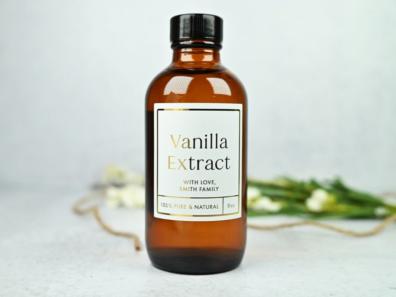 Puede incluir: Una botella de vidrio marr&oacute;n de extracto de vainilla con tapa negra. La etiqueta blanca presenta texto dorado que dice "Vanilla Extract" y "With Love, Smith Family". La botella contiene 237 ml de extracto de vainilla 100% puro y natural.