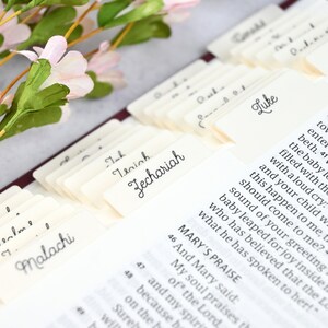May include: Close-up of a Bible with index tabs for each book of the Bible. The tabs are labeled with the names of the books, including Malachi, Zechariah, Luke, and Mark. The Bible is open to the book of Luke, and the text is visible.