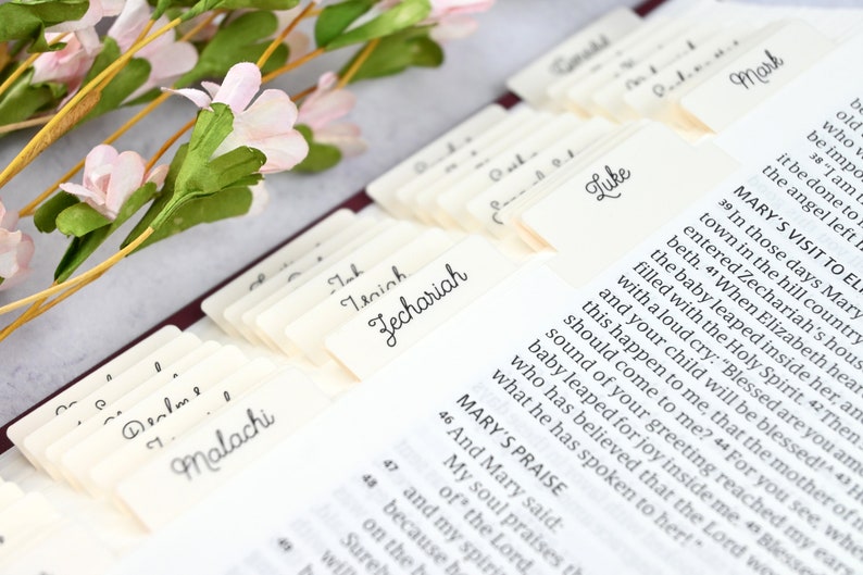 May include: Close-up of a Bible with index tabs for each book of the Bible. The tabs are labeled with the names of the books, including Malachi, Zechariah, Luke, and Mark. The Bible is open to the book of Luke, and the text is visible.