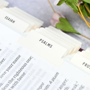 May include: Close-up of a white book with tabs labeled "Solomon", "Isaiah", "Psalms", and "Proverbs".