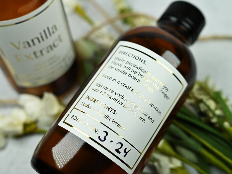 Puede incluir: Dos botellas de vidrio marr&oacute;n de extracto de vainilla con etiquetas doradas. Las etiquetas incluyen el texto "Extracto de vainilla", "Instrucciones" e "Ingredientes: Vodka y vainas de vainilla". Una botella est&aacute; etiquetada "Embotellado el: 3.24".