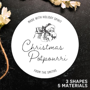 May include: A white circular label with the text "Made with Holiday Spirit" and "Christmas Potpourri" in elegant script. A vintage illustration of Santa Claus is featured. The label also includes "From The Smiths", "3 Shapes", and "5 Materials".