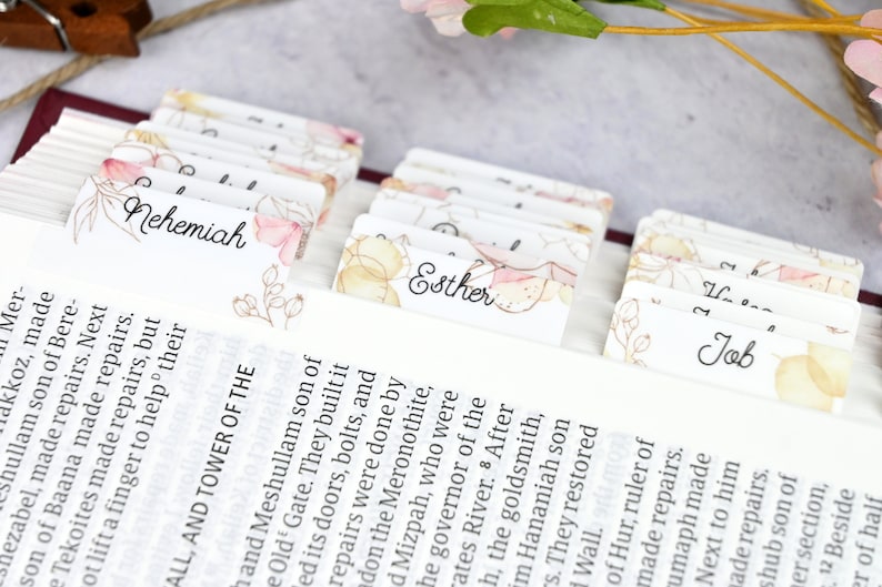 May include: Close-up of a Bible with colorful floral bookmarks for the books of Nehemiah, Esther, and Job. The bookmarks are made of paper and have a watercolor design.