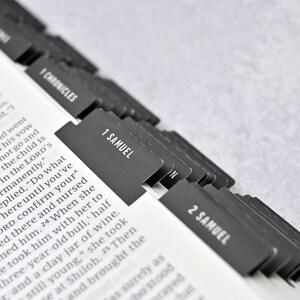 May include: Close-up of a Bible with black tabs marking the books of 1 Chronicles, 1 Samuel, and 2 Samuel. The tabs are arranged in a row, with the tab for 1 Samuel in the center.