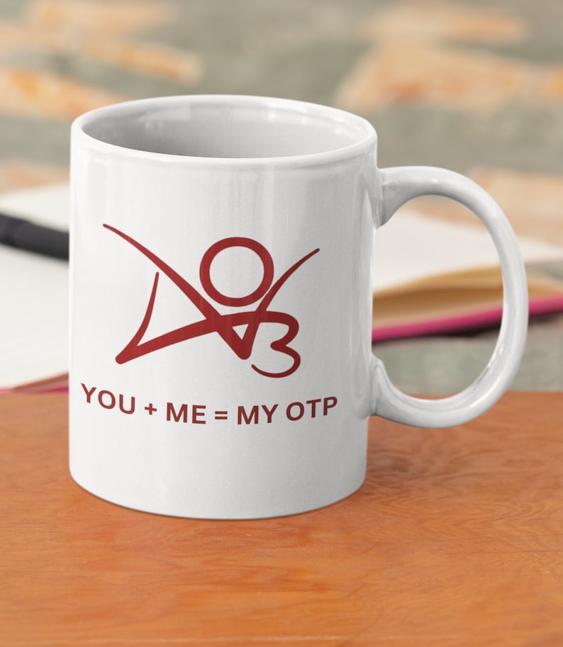 K&ouml;nnte beinhalten: Wei&szlig;e Keramiktasse mit einer roten Grafik einer stilisierten Person mit dem Text "YOU + ME = MY OTP" auf der Vorderseite.
