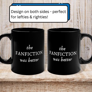 May include: Two black coffee mugs with white text that reads "the FANFICTION was better" on each side. The mugs are on a wooden surface.